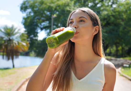 Young woman drinking green smoothie containing Power Shot Greens Superfoods.